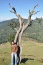 Full length of a stylish Indian young man looking at camera while posing with leaning against tree in the mountain Royalty Free Stock Photo