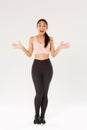 Full length of surprised and amazed female athelte, asian fitness girl in sportsbra and leggings looking wondered