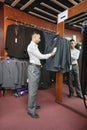 Full-length of tailor standing by the clothing rack of suits