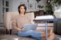 Full length of middle aged woman with headphone using a laptop while browsing on the internet at home Royalty Free Stock Photo