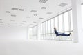 Full length of thoughtful young businessman relaxing on chair while looking through window at new empty office Royalty Free Stock Photo