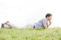 Full length of thoughtful young man lying on grass against clear sky Royalty Free Stock Photo