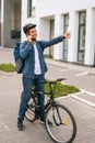 Full length vertical portrait of cheerful handsome bicycle delivery man talking on mobile phone, sees customer and marks Royalty Free Stock Photo