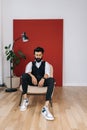 Full length vertical portrait of confident Indian businessman wearing elegant formalwear sitting on soft chair and Royalty Free Stock Photo