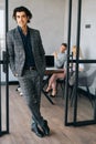 Full length vertical portrait of friendly businessman in suit standing in modern office , smiling looking at camera Royalty Free Stock Photo