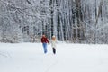 Full-length view of the adorable loving couple holding hands and happily running along the snowy forest.