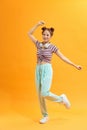 Full length view of attractive stylish asian woman jumping on yellow background Royalty Free Stock Photo