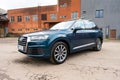 Full length view of Audi A6 wagon in blue metallic shades parked against industrial scenery. Luxury car with sleek