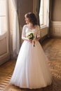 Full length view of beautiful woman posing in wedding dress near window at luxury interior Royalty Free Stock Photo