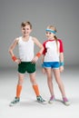 Full length view of cute smiling boy and girl in sportswear standing together on grey Royalty Free Stock Photo