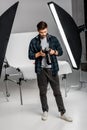 full length view of handsome professional young photographer using camera Royalty Free Stock Photo