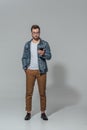 Full length view of handsome sylish young man in eyeglasses using smartphone Royalty Free Stock Photo
