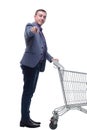 Full length view of handsome young man standing with shopping trolley and looking at camera Royalty Free Stock Photo