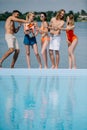 full length view of happy young male and female friends drinking champagne at poolside Royalty Free Stock Photo