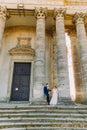 Full-length view of the newlyweds standing near the columns of the ancient building. Royalty Free Stock Photo