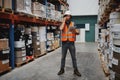 Full length of warehouse manager tracking supply order details using digital tablet while in conversation over mobile Royalty Free Stock Photo