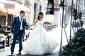 Full-length wedding shot of the charming young stylish newlyweds dancing in the old sunny town street.