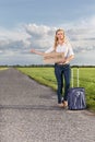 Full length of woman hitching while holding anywhere sign on country road