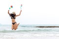 Full Length Of Woman Holding Pinwheel Toys While Jumping At Beach