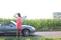 Full length of woman shielding eyes while holding map by convertible