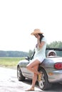 Full-length of woman using cell phone while leaning on convertible at countryside Royalty Free Stock Photo