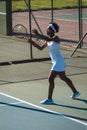 Full length of young african american female player serving tennis ball at court on sunny day Royalty Free Stock Photo