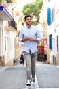 Full length young arabic man walking in city with mobile phone and earphones Royalty Free Stock Photo