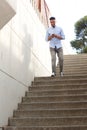 Full length young arabic man walking down steps with mobile phone Royalty Free Stock Photo