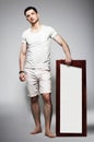 Full Length of Young Barefoot Man in White Shorts with Plackard