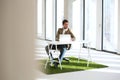 Full length of young businessman with laptop at desk on turf in new office Royalty Free Stock Photo