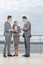 Full length of young businesspeople communicating on terrace against sky