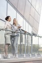 Full length of young businesswomen conversing at office balcony