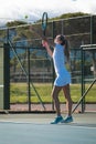 Full length of young caucasian female player serving ball with racket at tennis court on sunny day Royalty Free Stock Photo