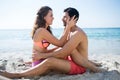 Full length of young couple sitting face to face at beach Royalty Free Stock Photo