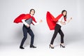 Full length of young couple wearing red superhero isolated on white background