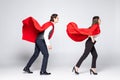 Full length of young couple wearing red superhero isolated on white background