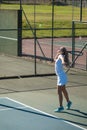 Full length of young female caucasian player serving ball with racket at tennis court on sunny day Royalty Free Stock Photo