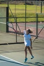Full length of young female caucasian player serving tennis ball at court on sunny day Royalty Free Stock Photo