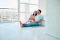 Full length of young happy mixed race couple sitting together on floor of their new apartment and drinking coffee Royalty Free Stock Photo