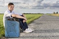 Full length of young man with empty gas can sitting by road Royalty Free Stock Photo