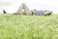 Full length of young man lying on grass against sky Royalty Free Stock Photo
