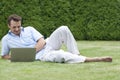 Full length of young man using laptop while lying on grass in park Royalty Free Stock Photo