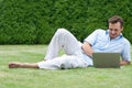 Full length of young man using laptop while lying on grass in park Royalty Free Stock Photo