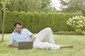 Full length of young man using laptop while reclining in park Royalty Free Stock Photo