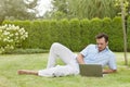 Full length of young man using laptop while reclining in park Royalty Free Stock Photo