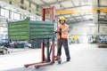 Full length of young manual worker pushing hand truck with heavy metal in industry Royalty Free Stock Photo