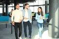 Full length of young people in smart casual wear discussing business and smiling while walking through the office. Royalty Free Stock Photo