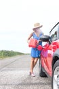 Full length of young woman refueling car on country road