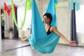 Adult woman practices anti-gravity yoga position in studio