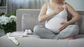 Full of maternal instincts woman gently touching her beloved pregnant tummy